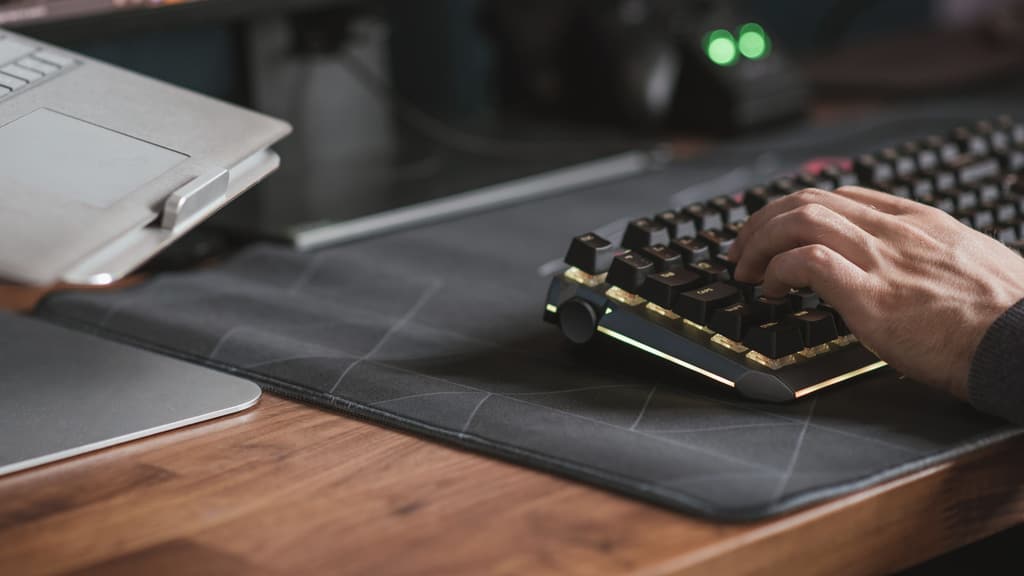 A hand at a keyboard on a desk in an evening office